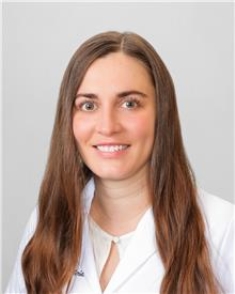 a woman in a white lab coat is smiling for the camera