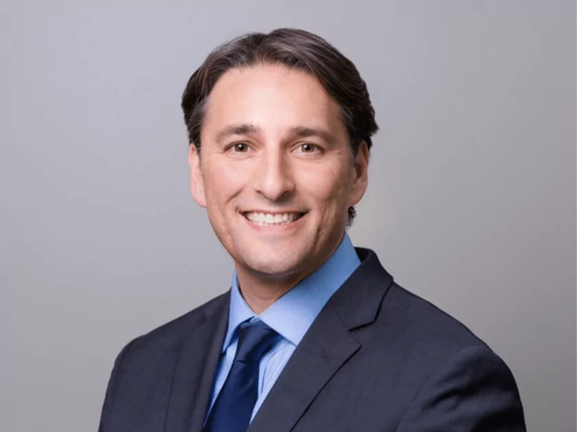 a man in a suit and tie smiles for the camera