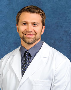 a man in a white coat and tie is smiling for the camera .