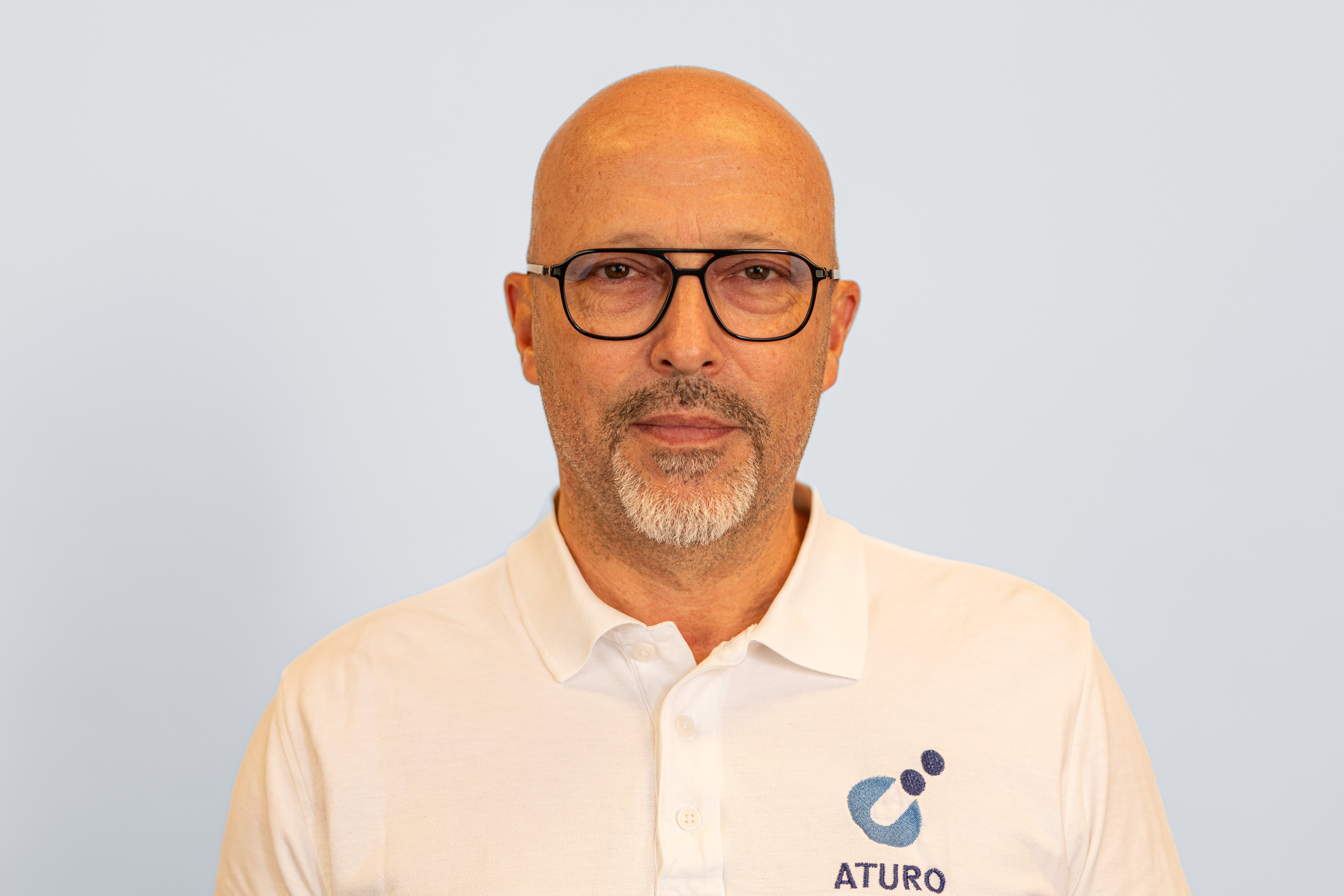 a man wearing glasses and a white shirt that says aturo