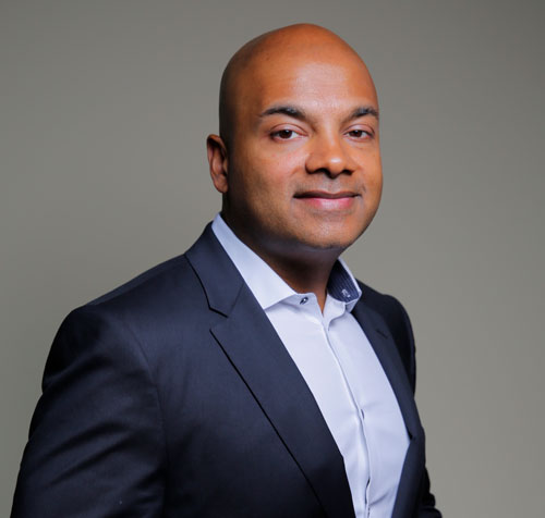 a man in a suit and white shirt smiles for the camera