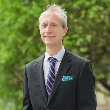 a man in a suit and tie is smiling for the camera .