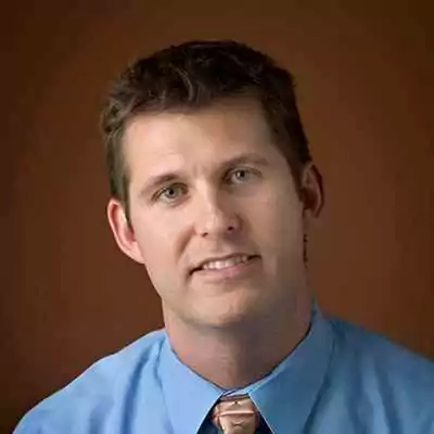 a man in a blue shirt and tie is smiling for the camera .