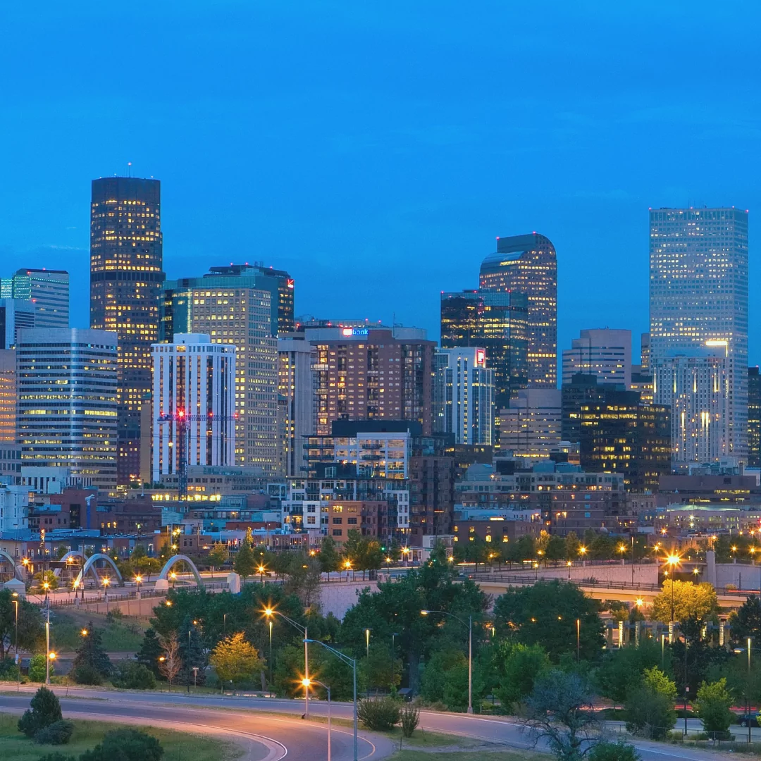 a city skyline at night with a bridge in the foreground