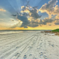 the sun shines through the clouds over the beach