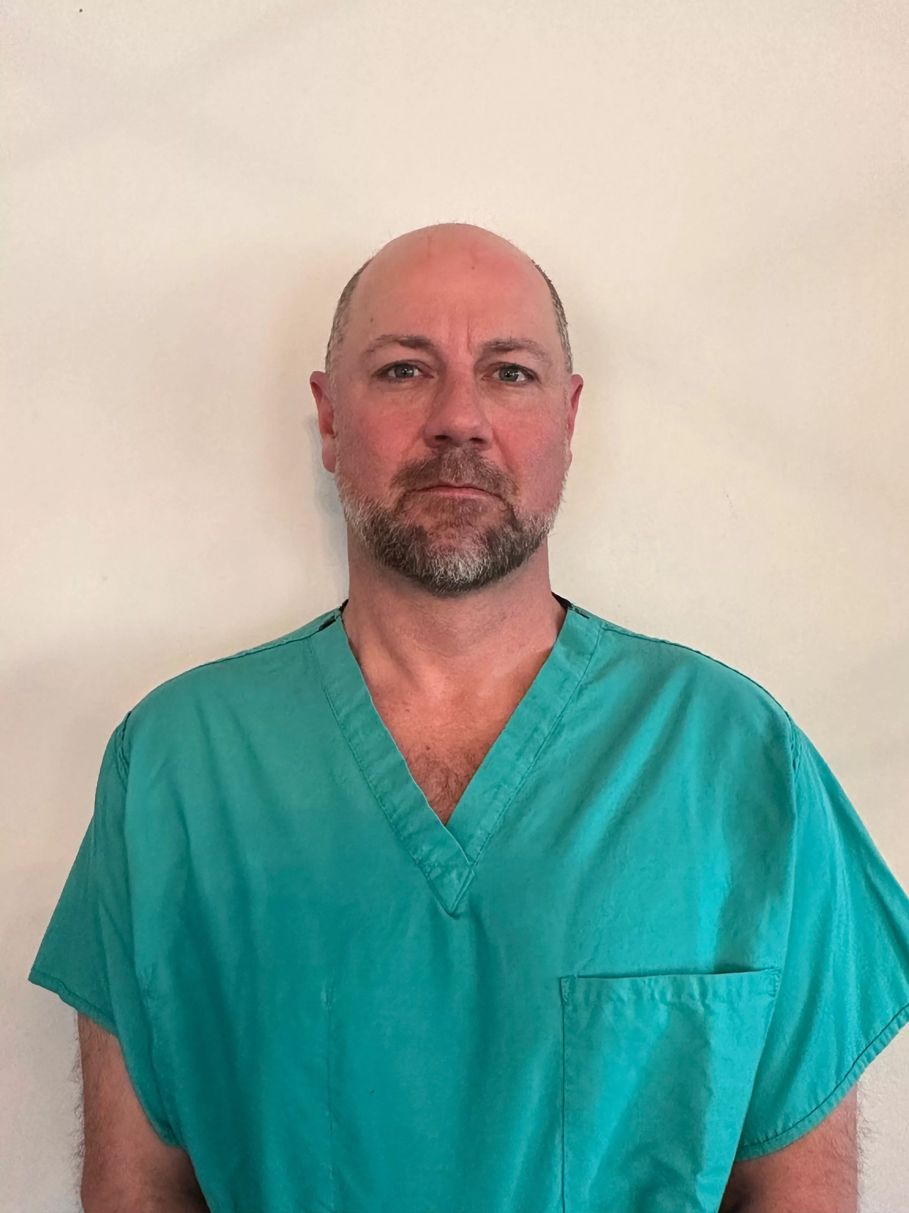 a man with a beard is wearing a green scrub top